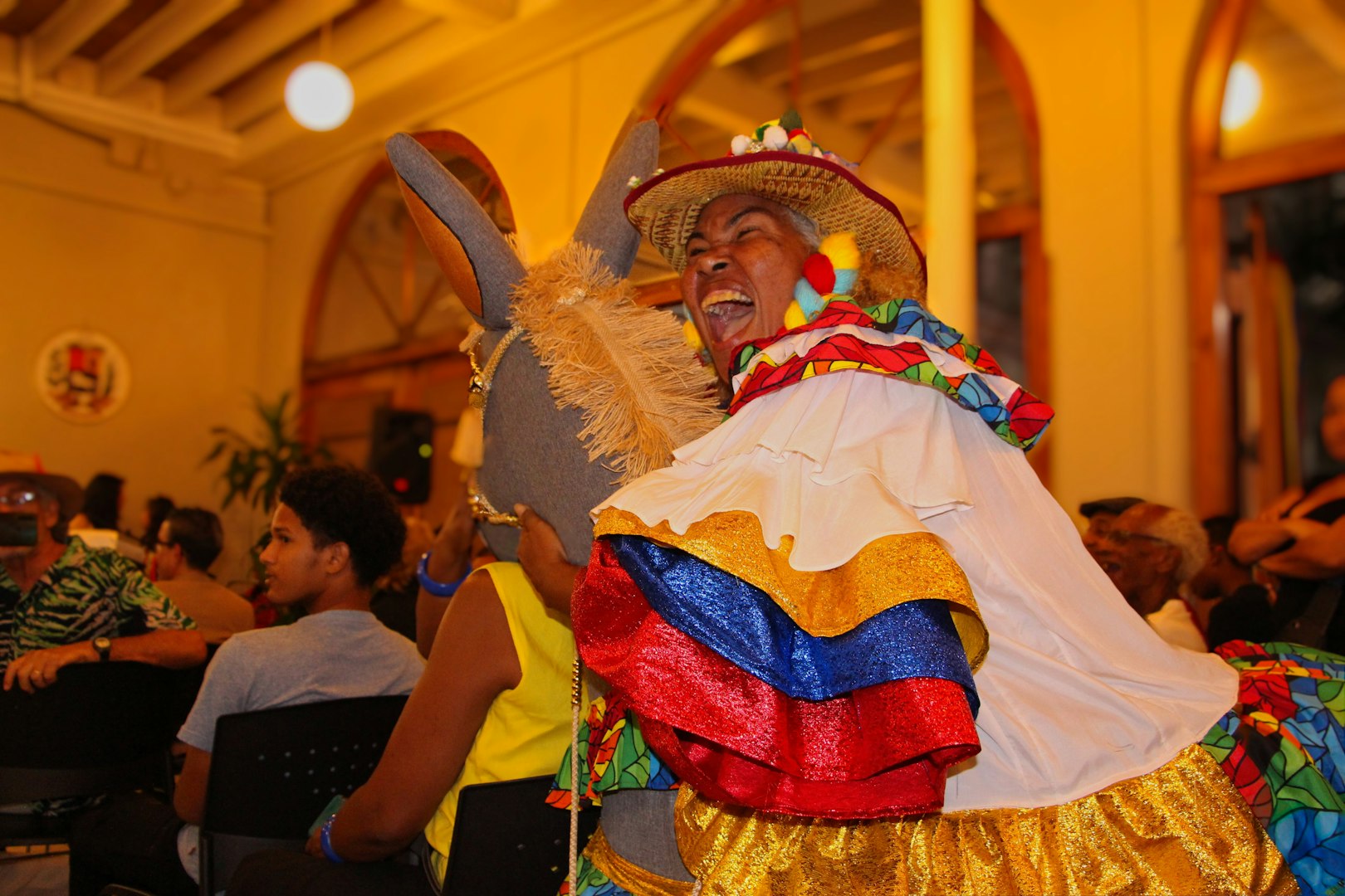 Woman in colorful costume dances with donkey float